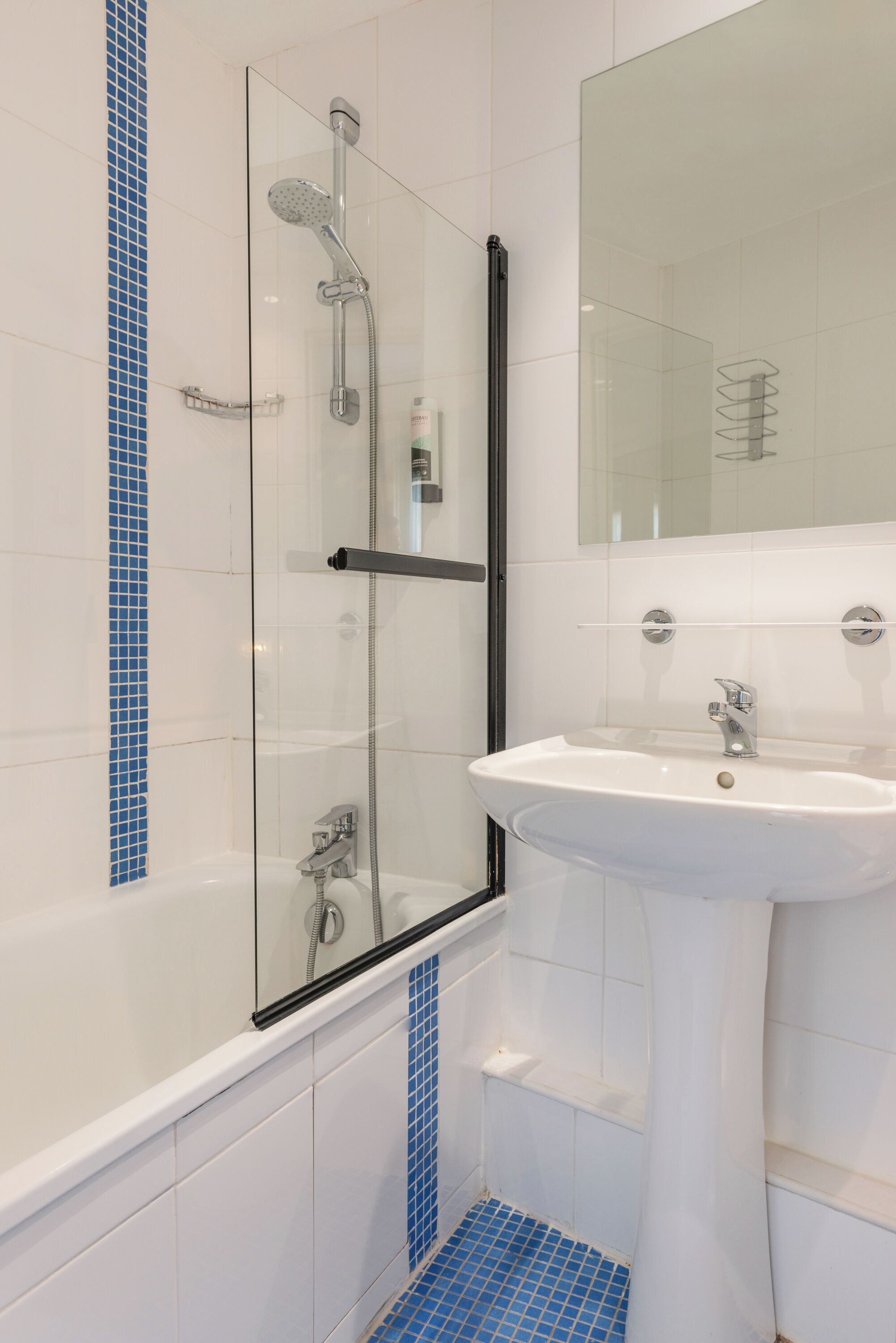 A modern bathroom with a glass-enclosed shower, a white sink, and blue-tiled accents.