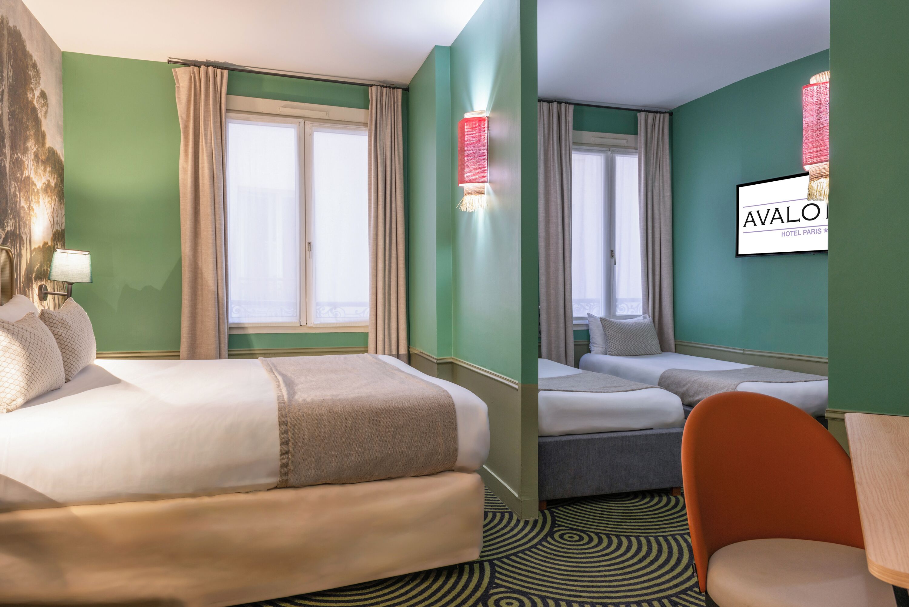 Ein Hotelzimmer mit zwei Betten, einem Sessel und einer Wandleuchte.