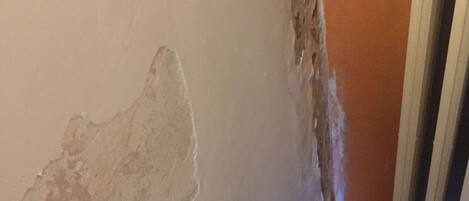 A wall with peeling paint and a radiator.