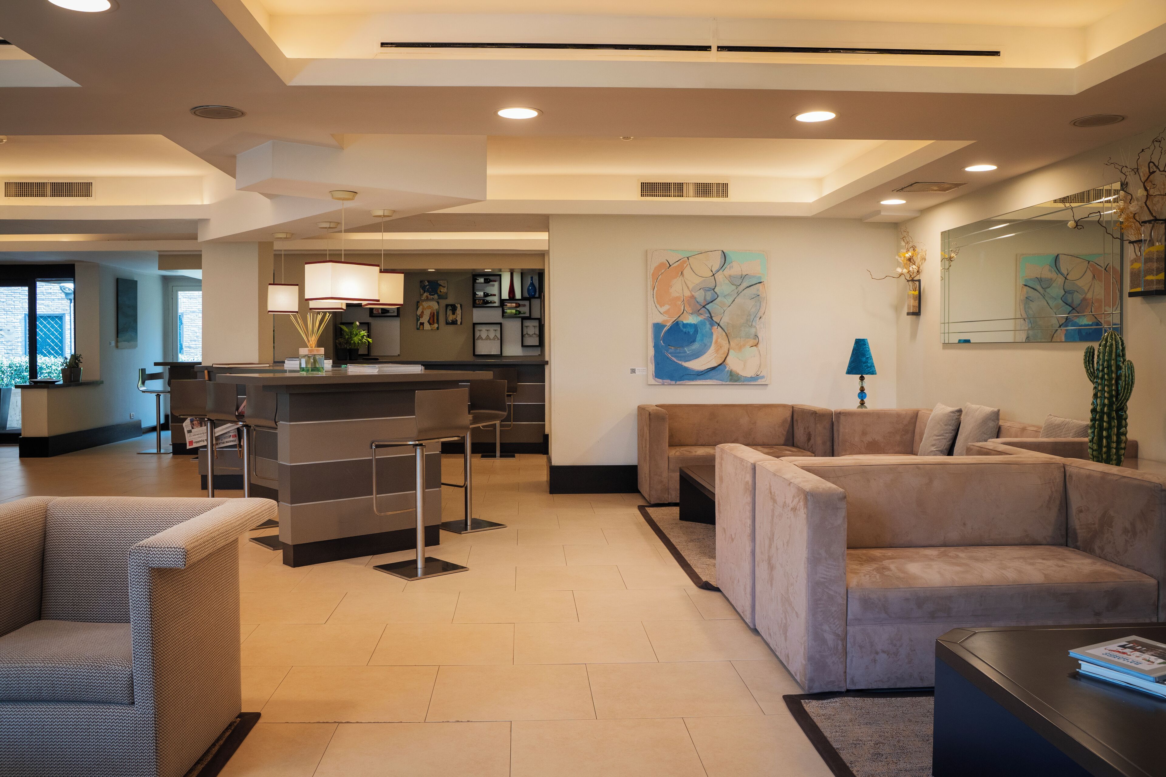 A modern hotel lobby with a reception desk, seating area, and artwork on the walls.