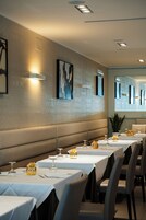 A restaurant with multiple tables set for dining, featuring a patterned wall and modern lighting.