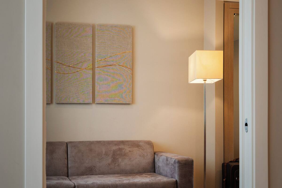 A neutral-toned room with a beige sofa, a standing floor lamp, and abstract wall art.