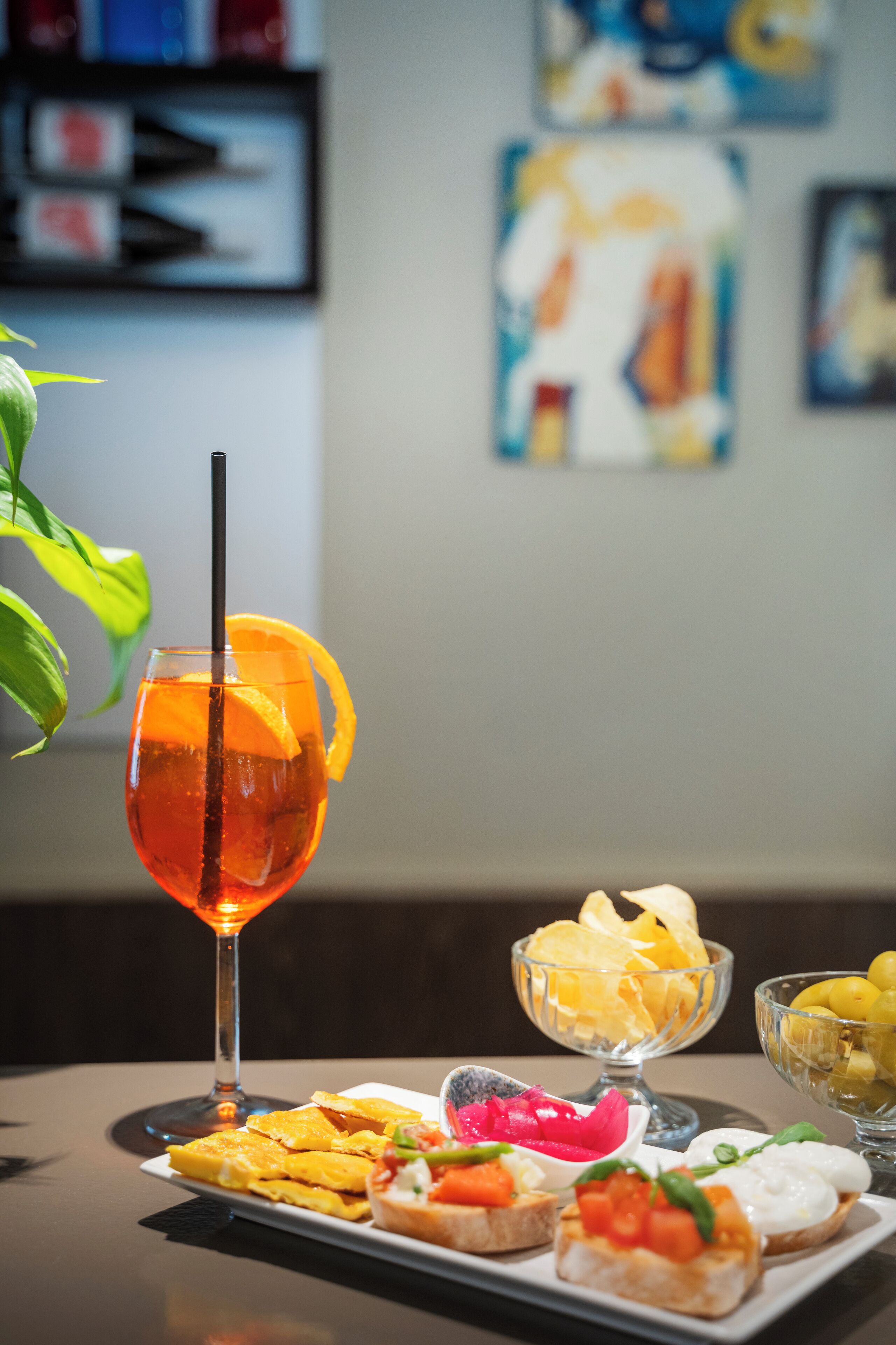 Ein Tisch mit einem Glas Orangensaft, einer Schüssel Chips und einer Platte mit Vorspeisen.