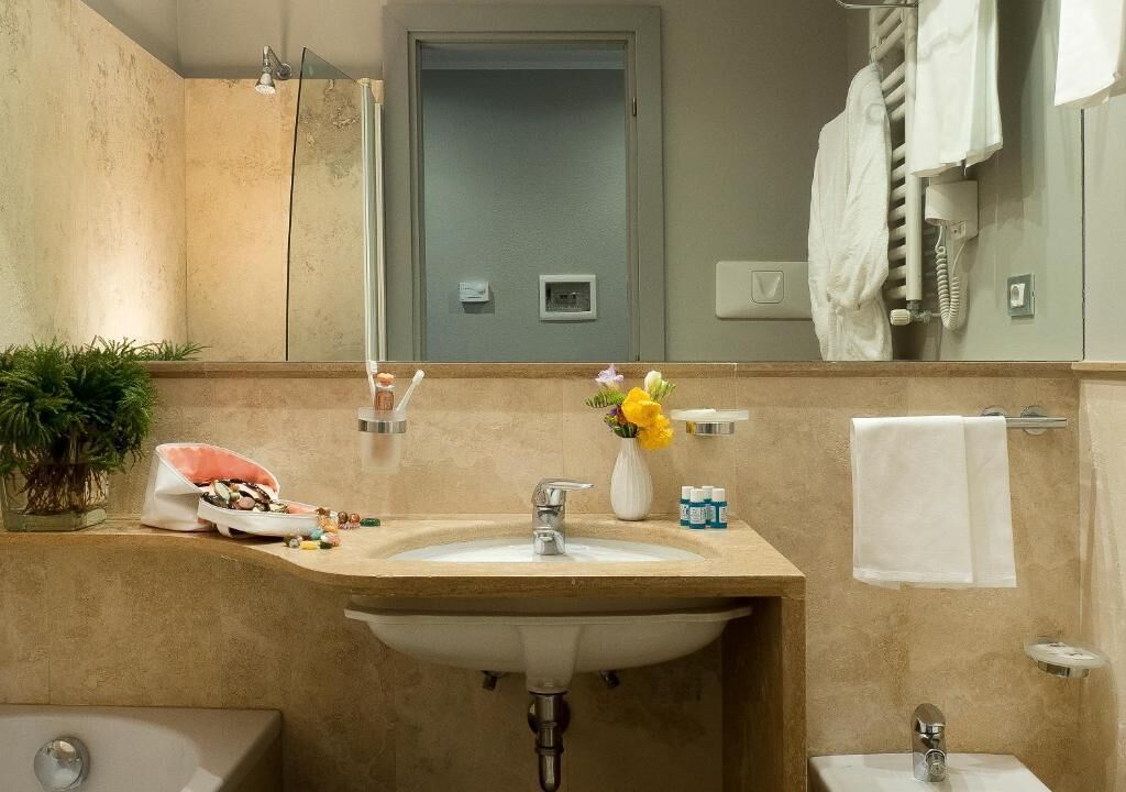 A bathroom with a sink, mirror, towel rack, and shower.