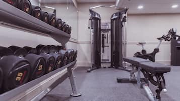 A gym with dumbbells, weight machines, and a bench.