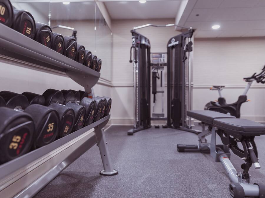 A gym with dumbbells, weight machines, and a bench.