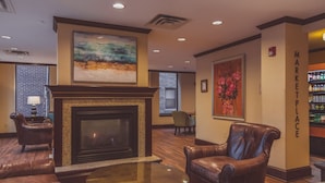 A lobby with a fireplace, leather chairs, a round table, and artwork on the walls.