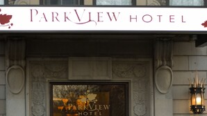 Entrada del Hotel Parkview con un letrero llamativo, detalles de cantería decorativa y una exhibición floral en primer plano.