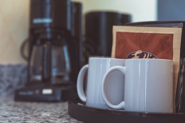 Una bandeja con dos tazas blancas y un paquete de cápsulas de café sobre una encimera de cocina.