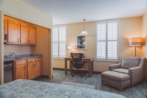 A compact hotel room with a kitchenette, a desk, a chair, a sofa, and a bed. - The Parkview Hotel (Syracuse)