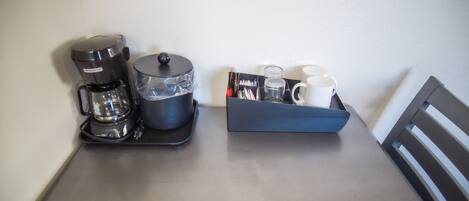 A coffee maker, a glass carafe, and a mug holder on a table.