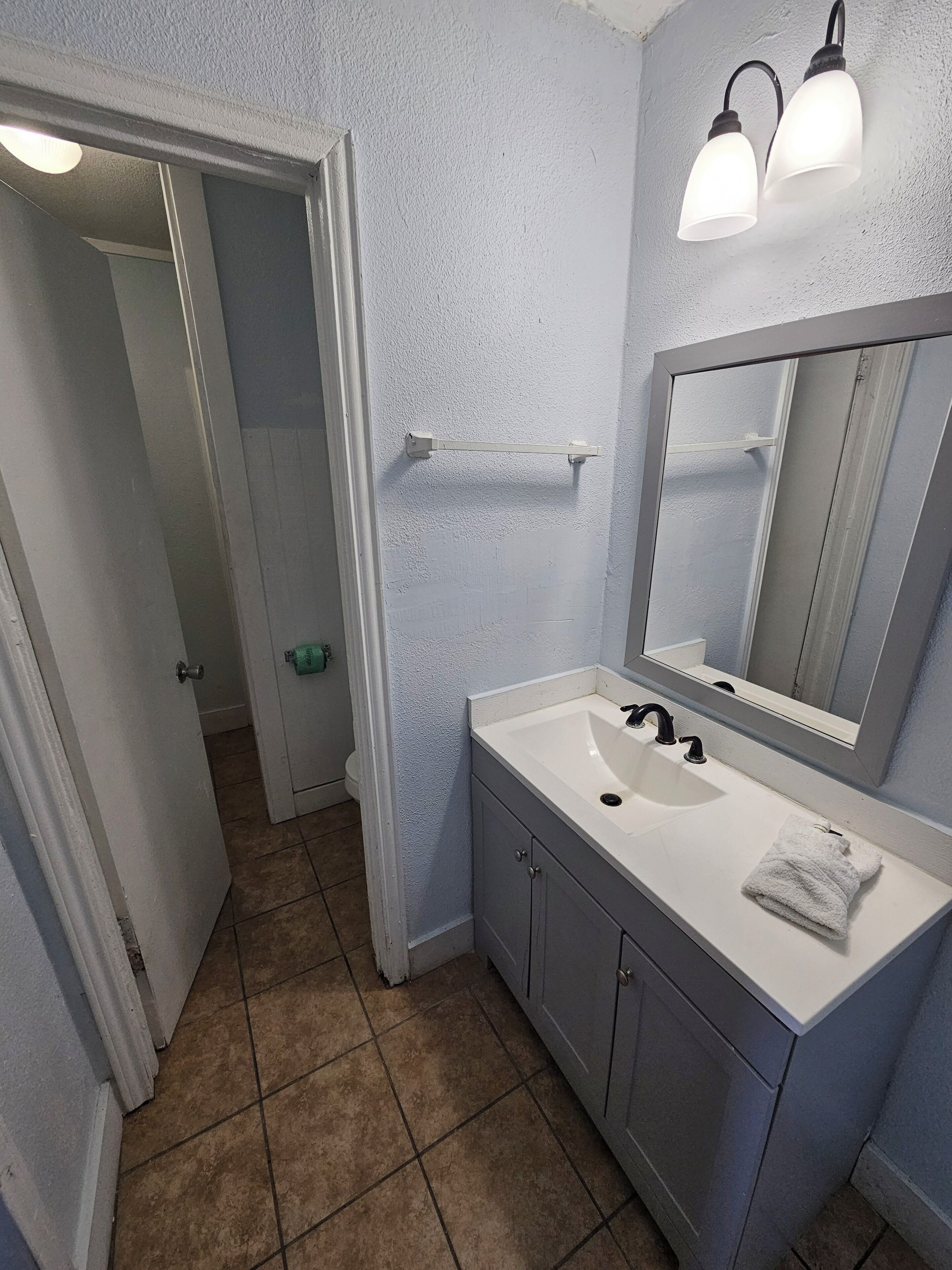 A bathroom with a white sink, a mirror, and a towel.