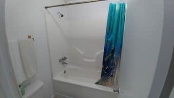 Un baño con bañera, inodoro y cortina de ducha.
