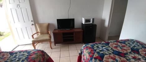 Een kamer met twee bedden, een televisie, een magnetron, een klein kastje en een stoel.