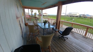A covered outdoor area with a table and chairs, a ceiling fan, and a view of a green landscape with buildings in the background. - Anchor Motel & RV Park (Freeport)