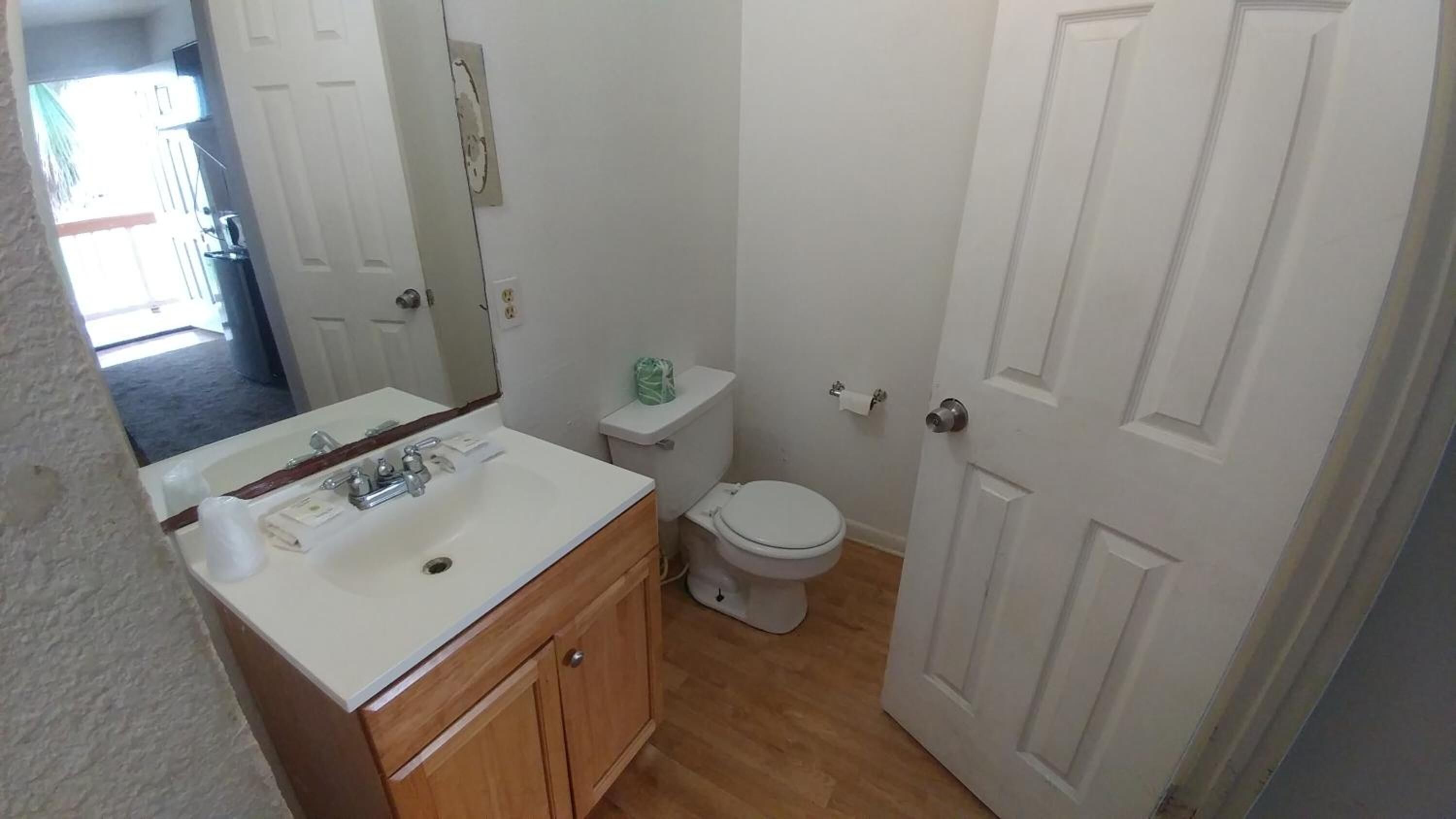 A bathroom with a white sink, toilet, and door.