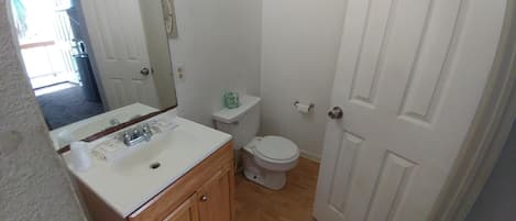 A bathroom with a white sink, toilet, and door.