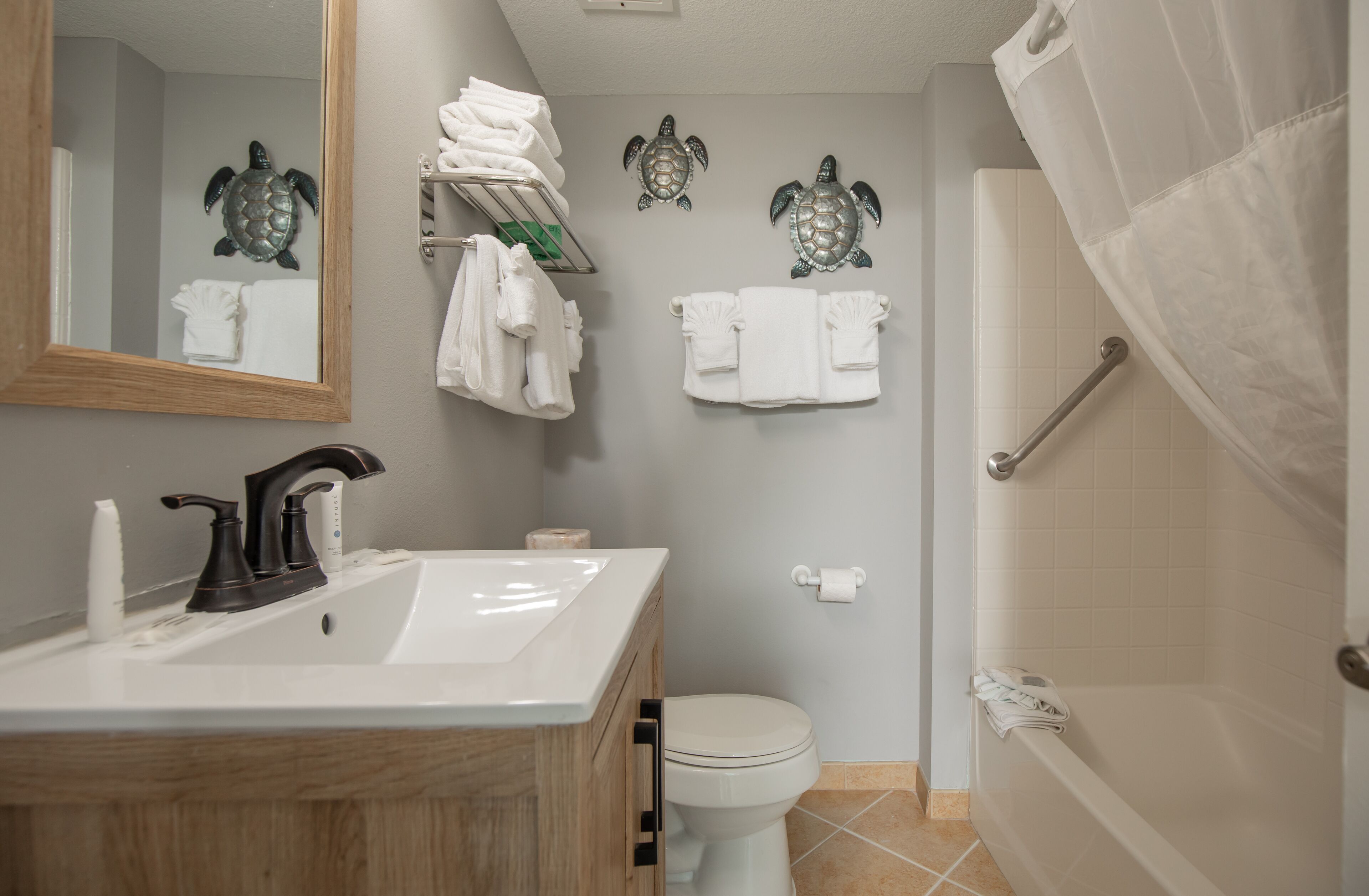 A bathroom with a sink, toilet, and bathtub. There are towels and a shower curtain.