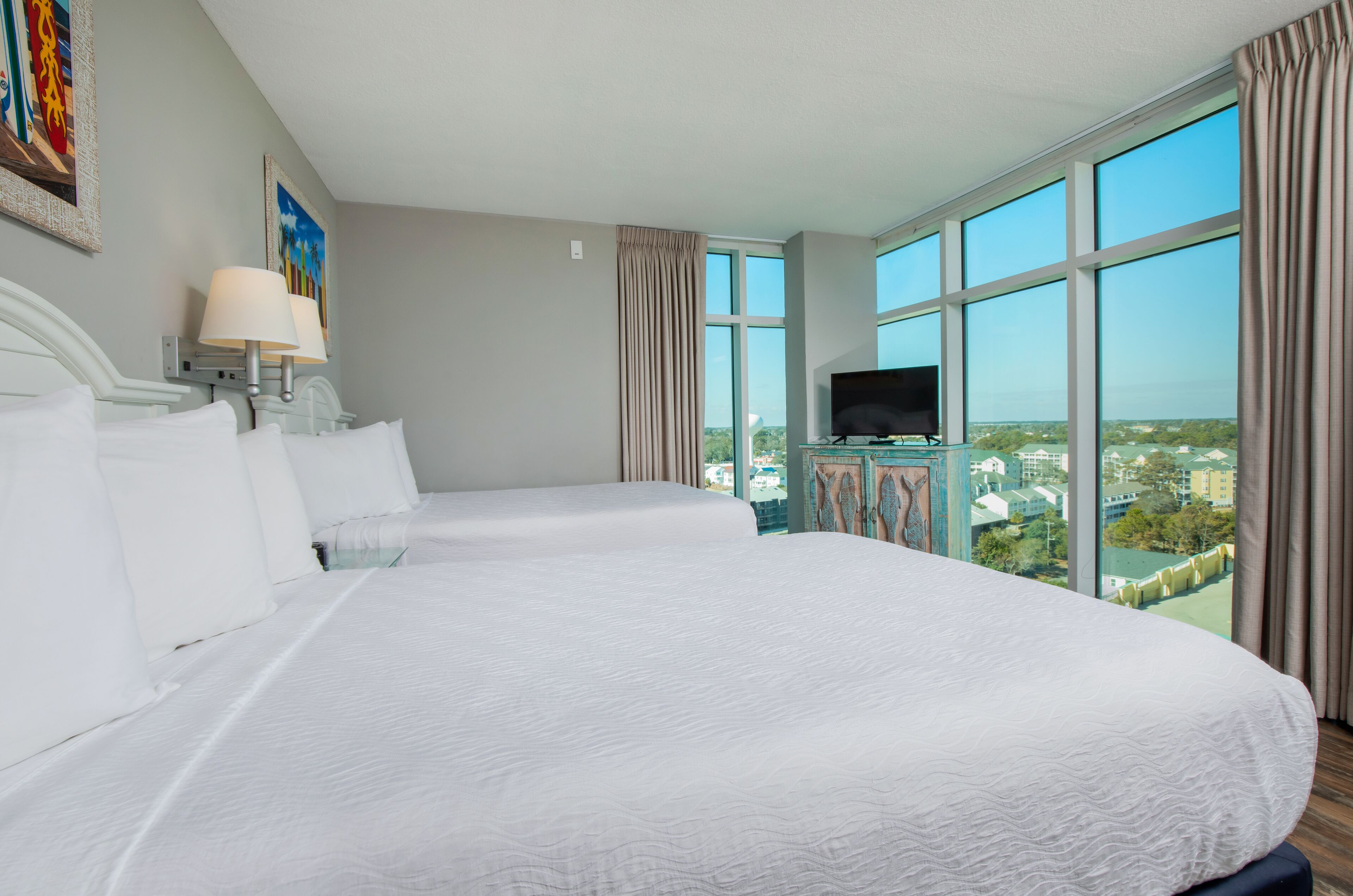 Une chambre d’hôtel avec deux grands lits, une télévision et une vue sur la ville.