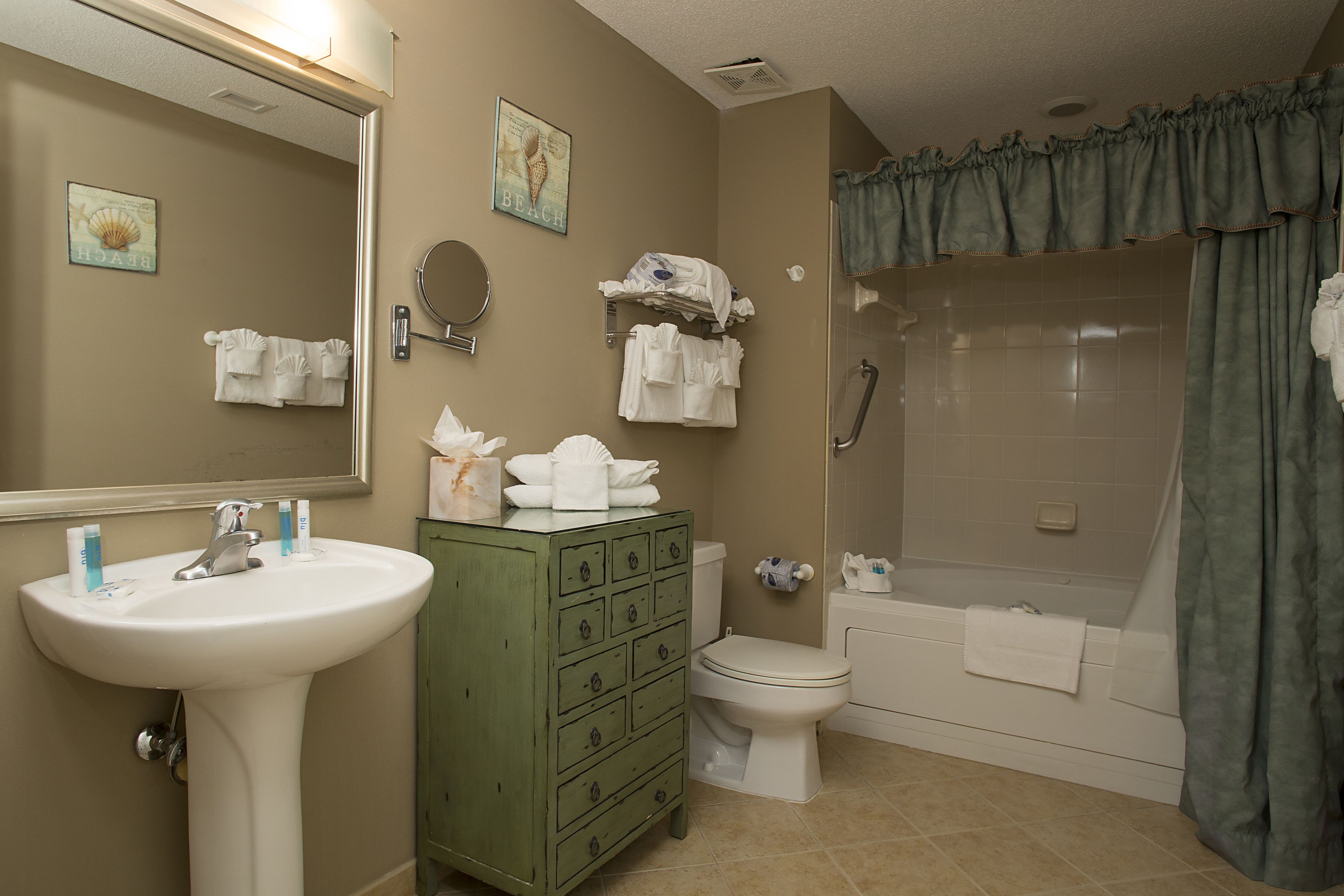 A bathroom with a sink, toilet, and shower. There are towels and toiletries on the counter.