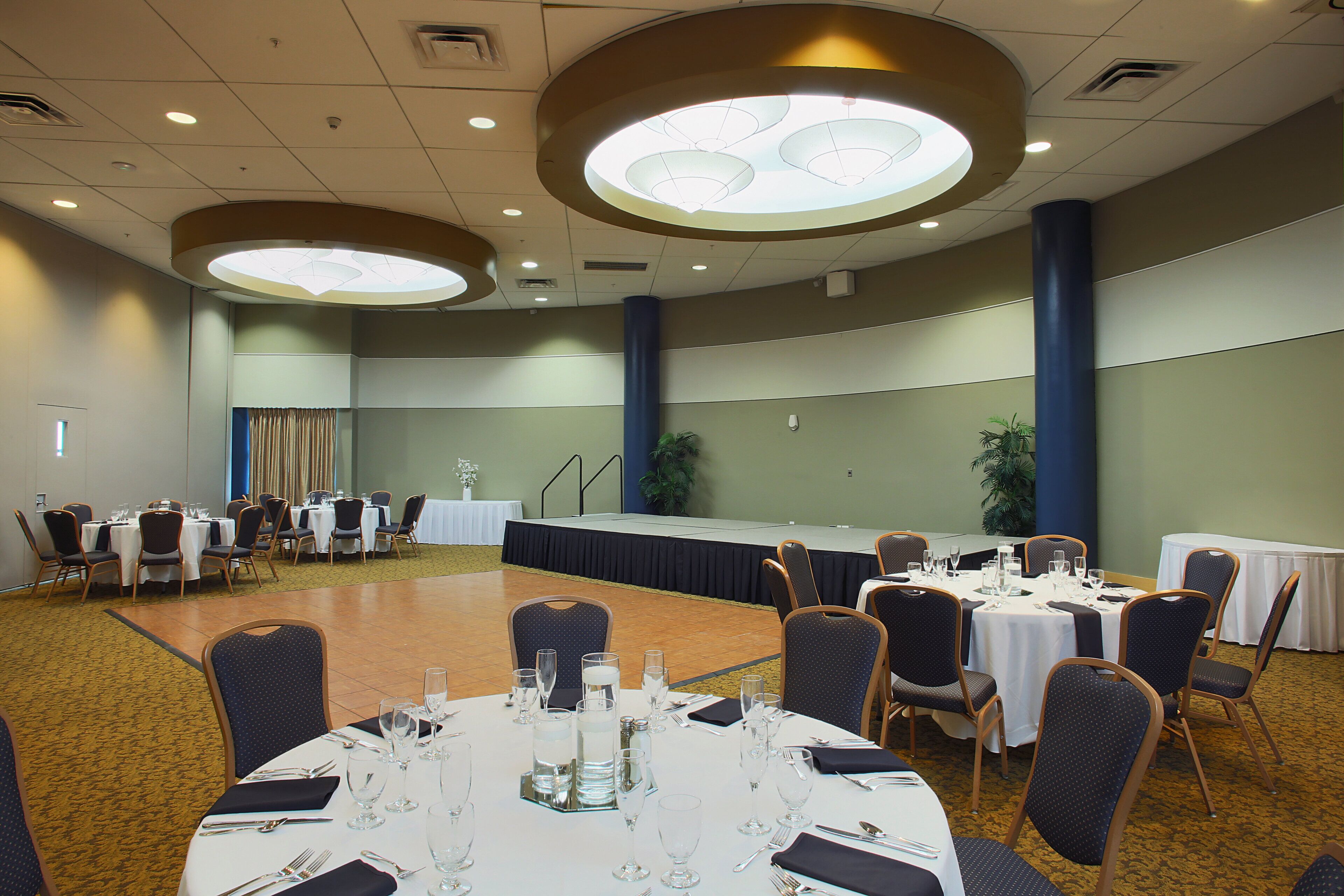 A conference room with round tables, chairs, and a stage.