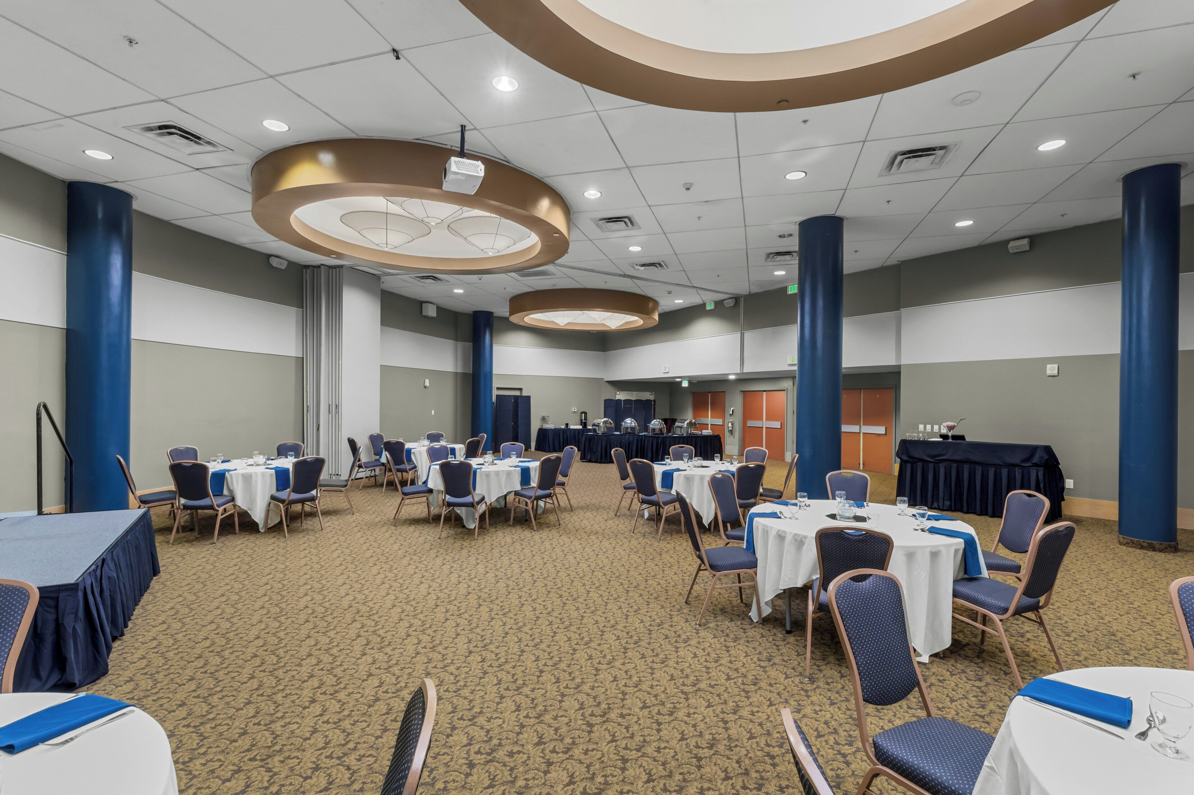 A conference room with round tables, chairs, and a stage area.