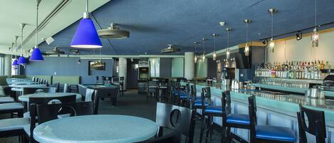 A bar area with multiple tables and chairs, a bar counter with bottles, and hanging blue pendant lights.