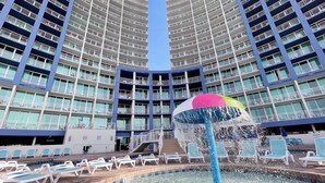 A pool area with lounge chairs and a water feature. - Avista Resort (North Myrtle Beach)
