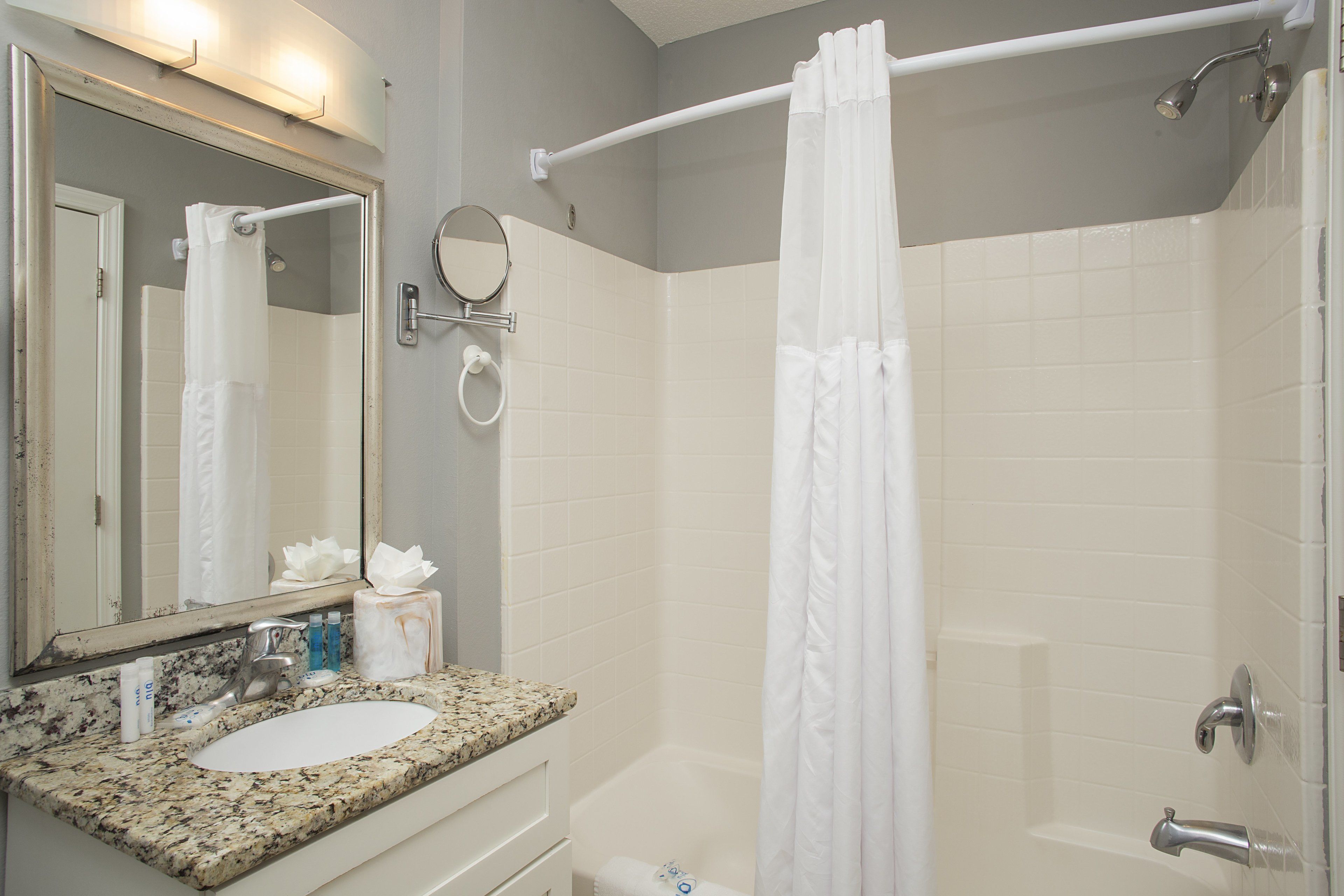 A bathroom with a sink, mirror, and shower area.