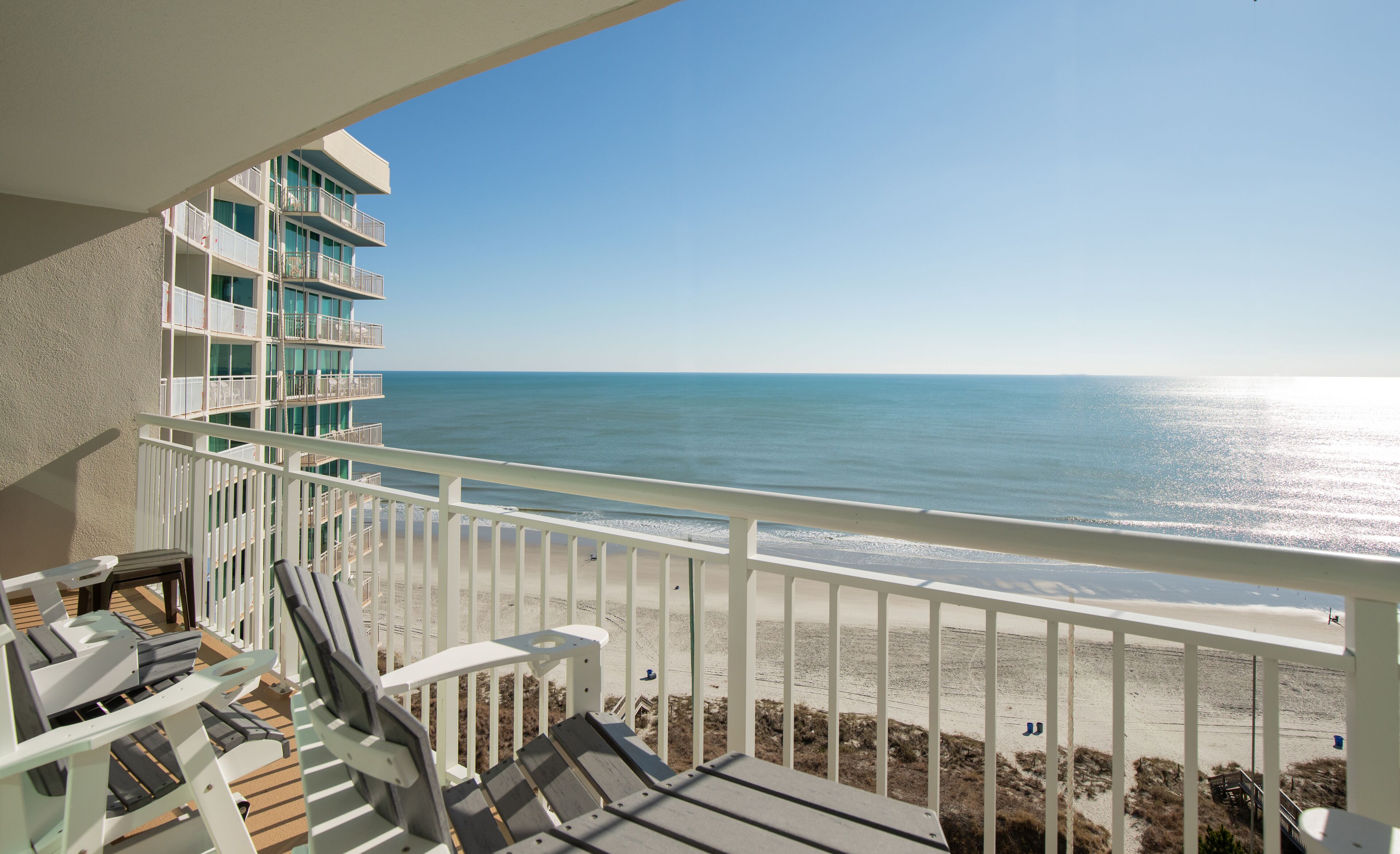 A balcony with a view of the beach and ocean.