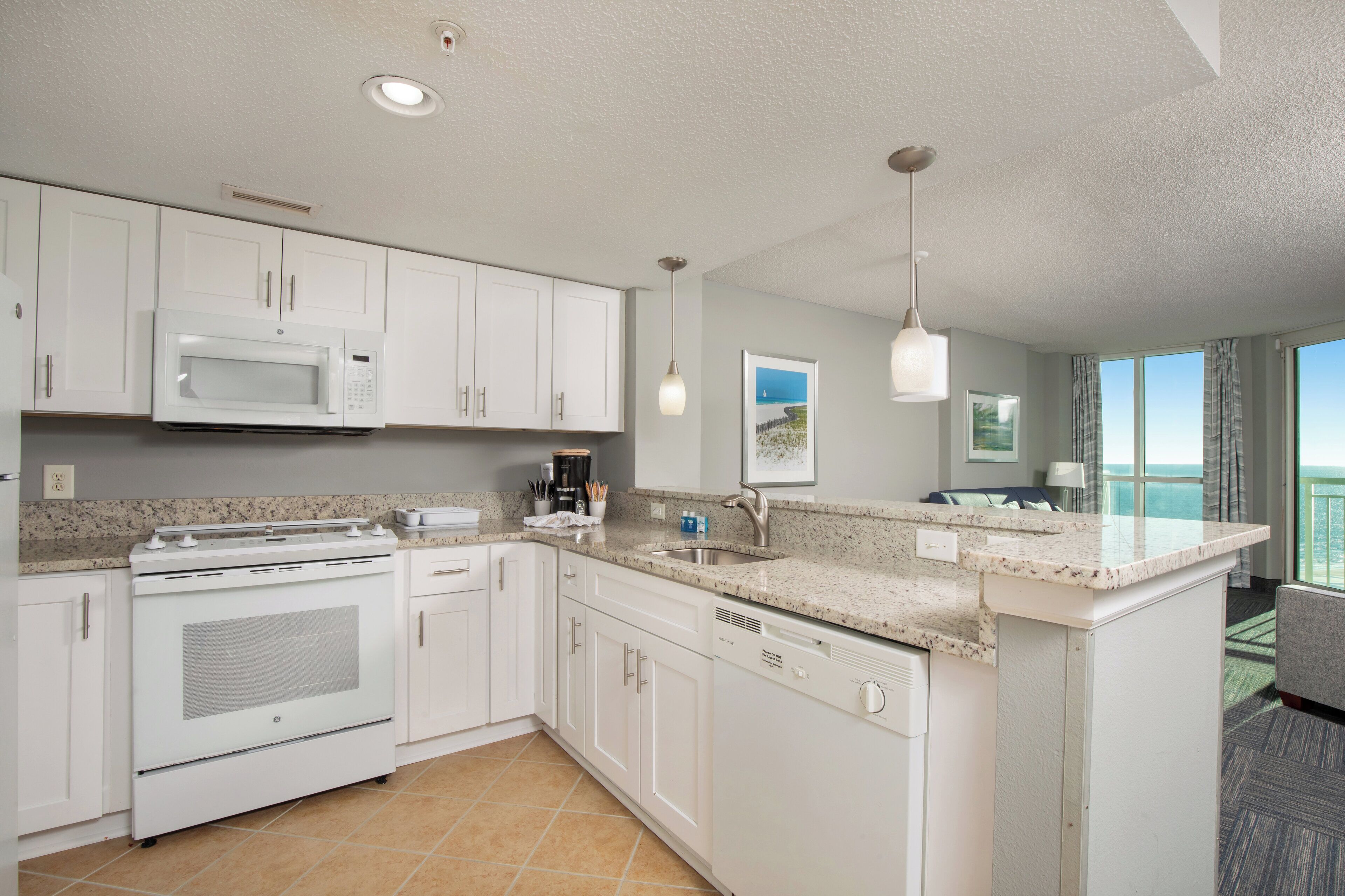 A modern kitchen with white cabinets, a built-in microwave, and a large island with a sink.