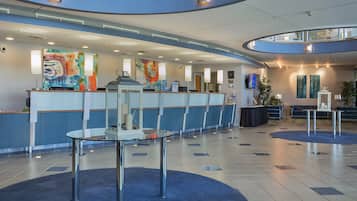 Welcome to our hotel lobby, featuring a curved reception desk, abstract art, and comfortable seating areas.