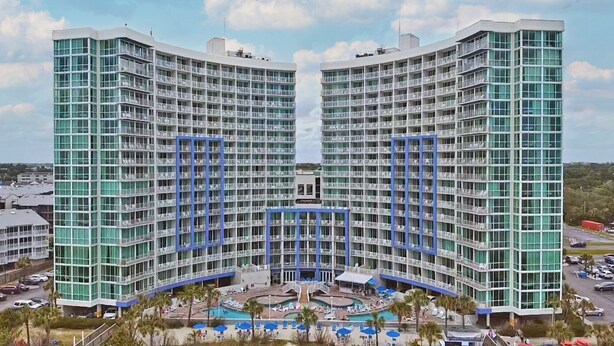 A high-rise hotel with a central courtyard, multiple balconies, and a pool area. - Avista Resort (North Myrtle Beach)