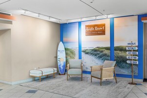 Un área de recepción con un mural con temática playera, una tabla de surf y señalización.