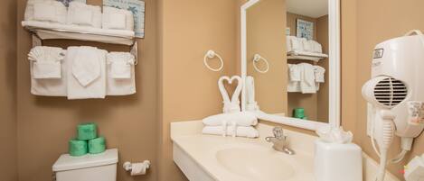 A bathroom with a beige wall, a sink, a mirror, and a towel rack with neatly folded towels.