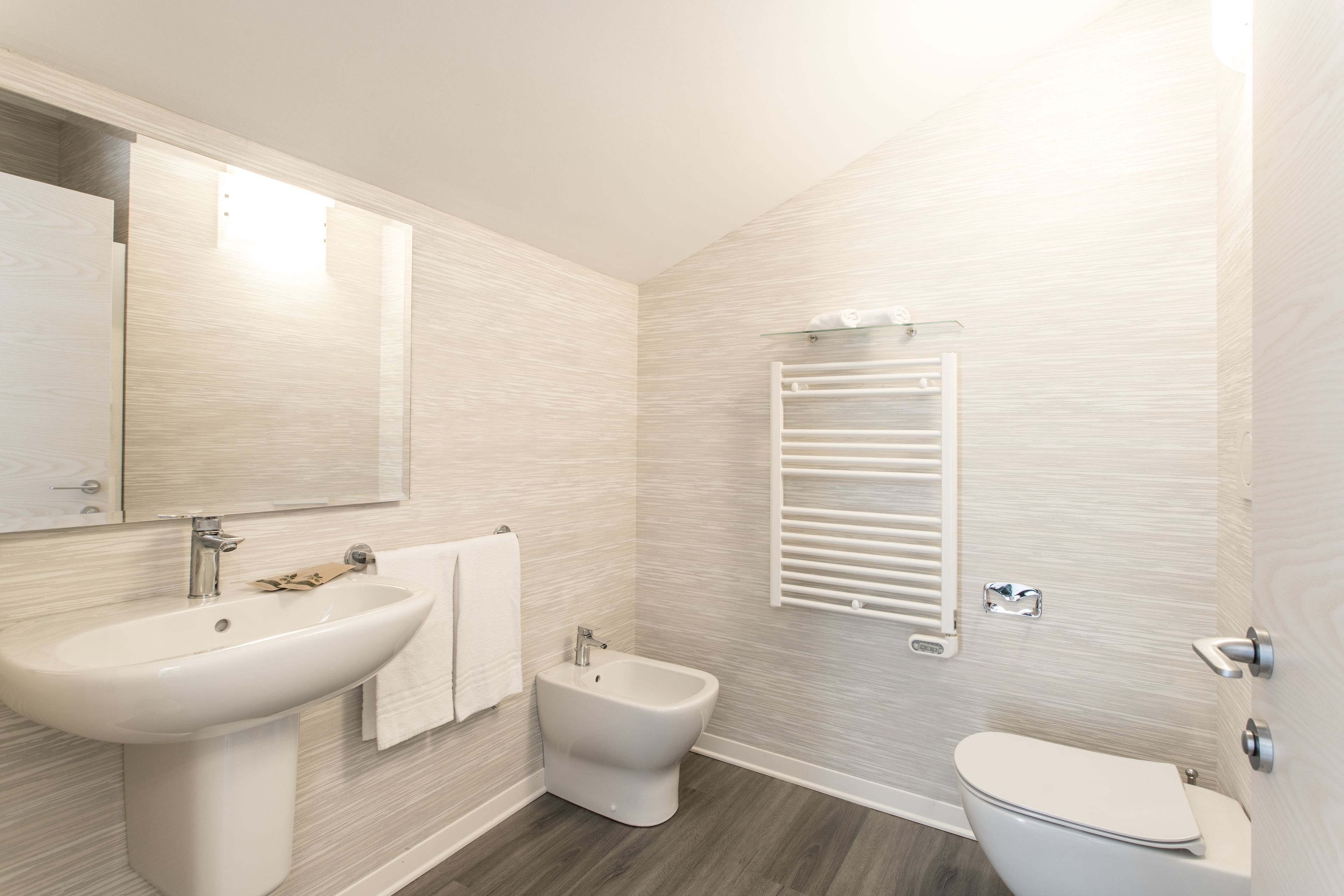 Un baño moderno con lavamanos pedestal, un bidé y un inodoro.
