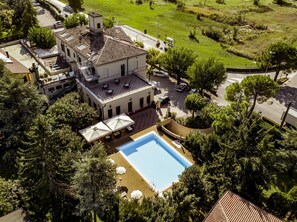 A large building with a swimming pool, surrounded by trees and a grassy area. - Hotel Dogana (Sirmione)