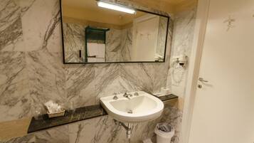 Un bagno con un lavabo in marmo, un grande specchio e un portasciugamani.