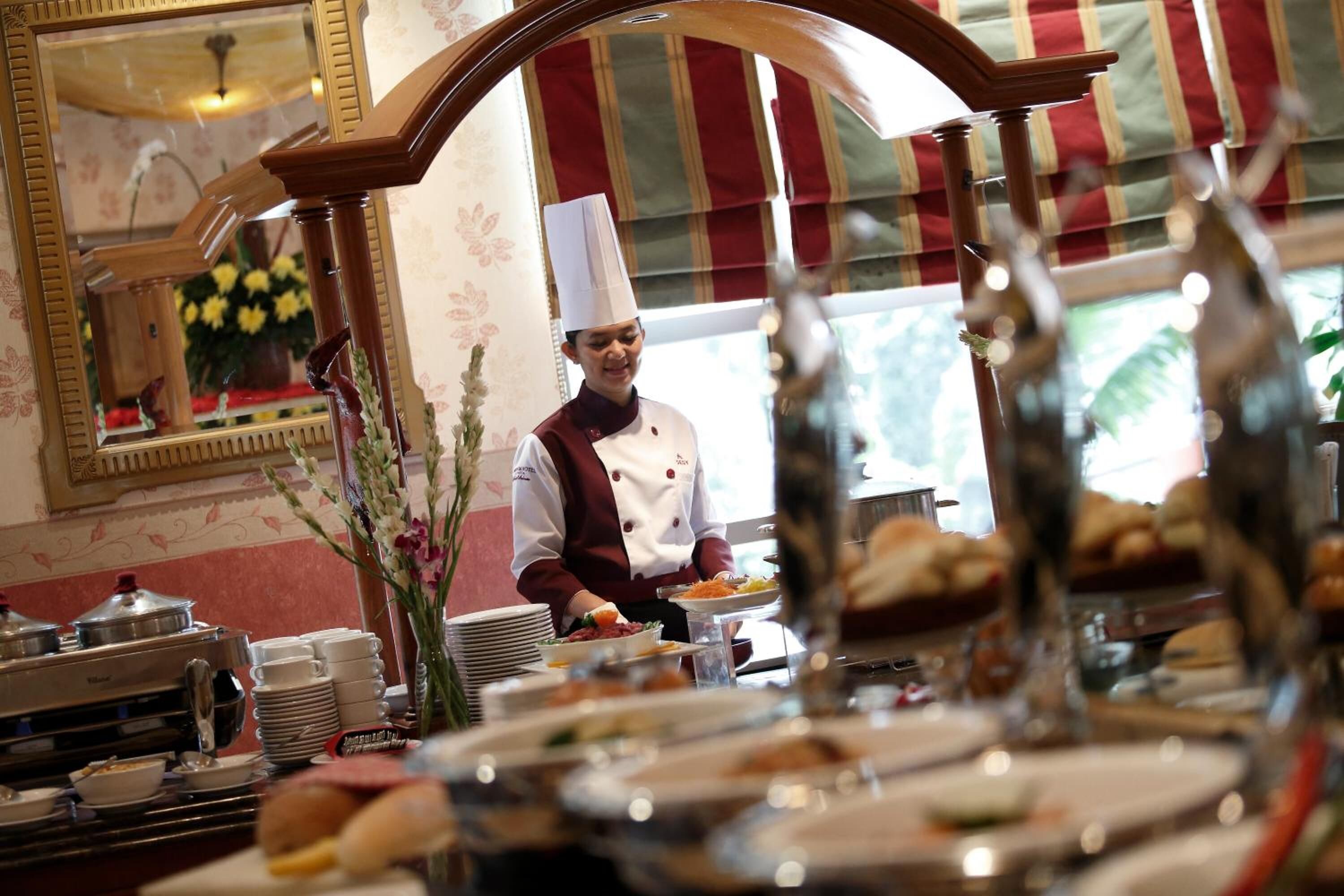 Montaje de bufé con diversos alimentos y un chef con uniforme.