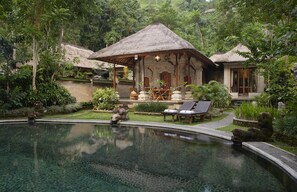 A pool with a thatched-roof structure, surrounded by lush greenery and a small waterfall. - Royal Pita Maha (Ubud)