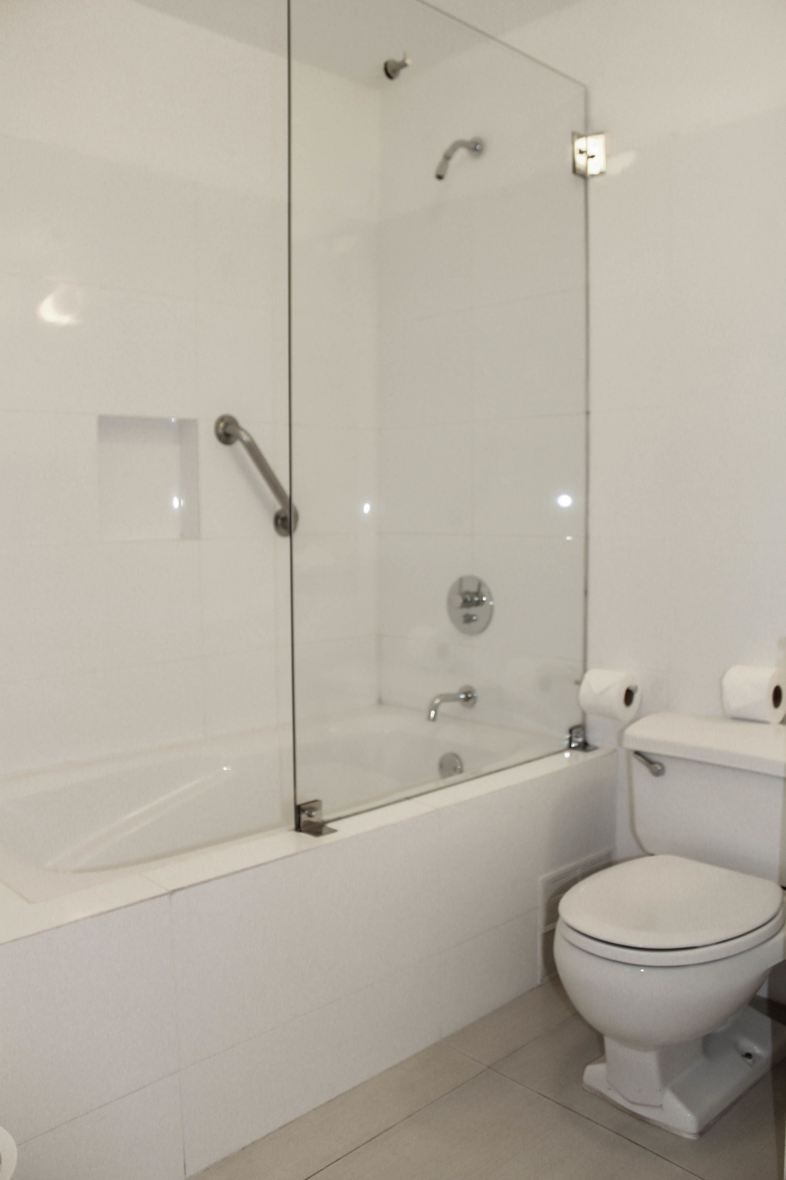 A modern bathroom with a glass-enclosed shower, a white toilet, and a bathtub.