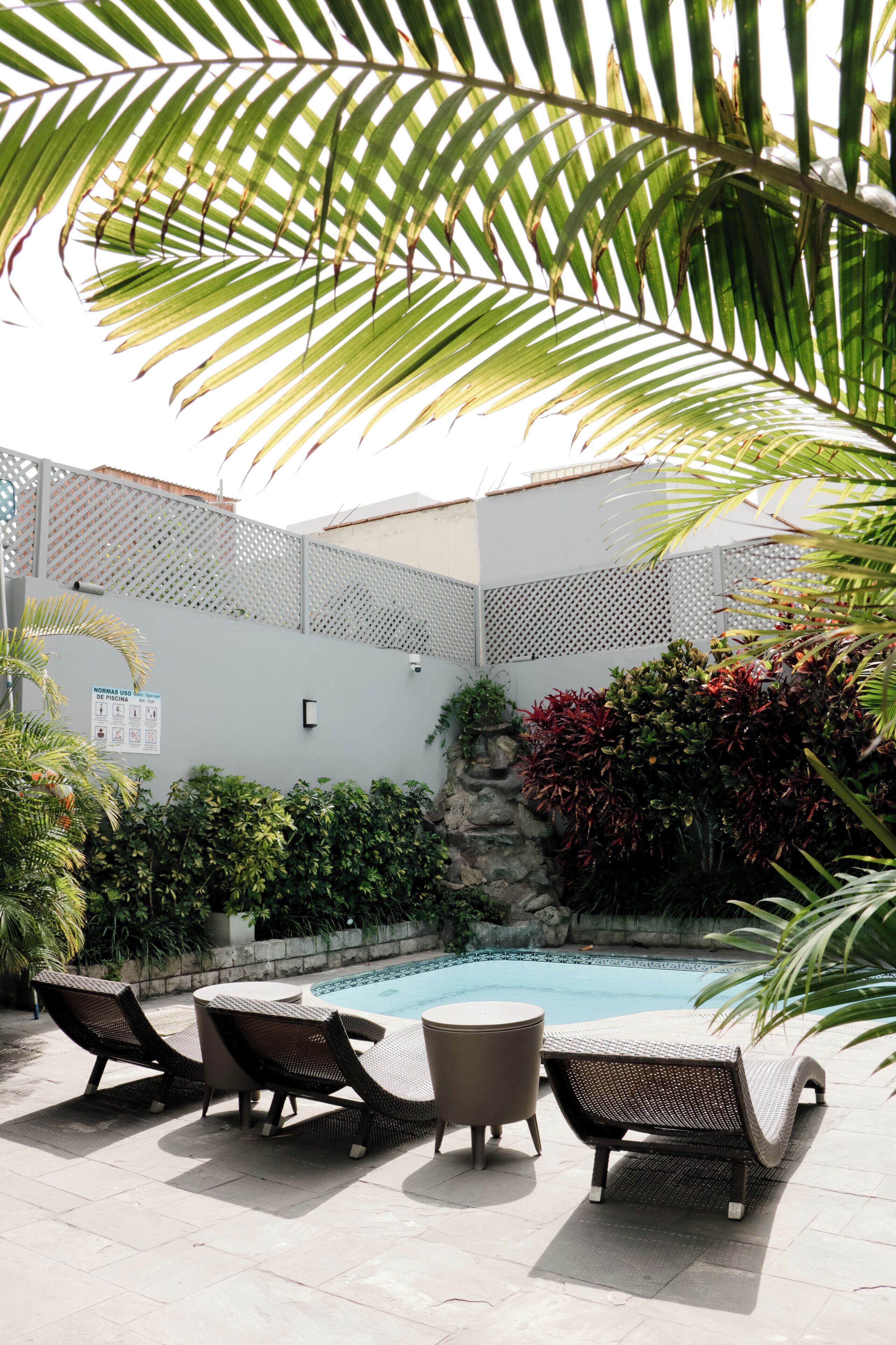 A poolside area with lounge chairs, a small table, and a pool.