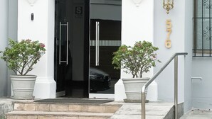 Un edificio con fachada blanca, puerta de entrada negra y el número '576' en la pared.
