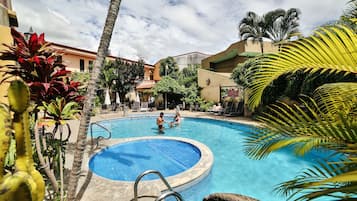 Relax by the pool surrounded by lush tropical plants and palm trees.