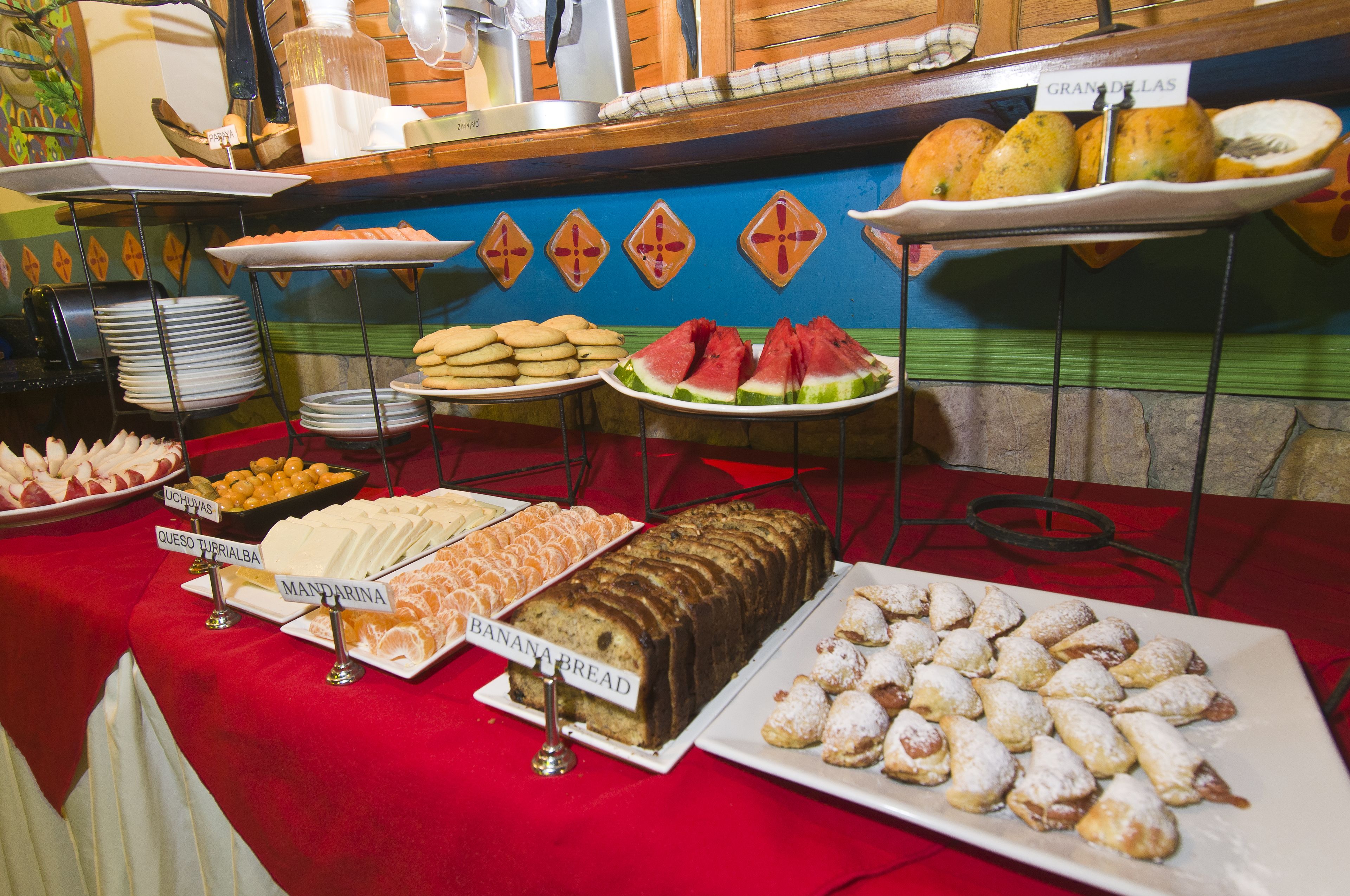 A buffet with various food items including bread, pastries, and fruits.