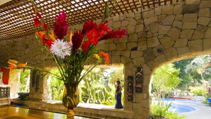 A stone wall with a window overlooking a garden. - Adventure Inn (Ulloa)