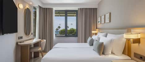 Une chambre d’hôtel équipée d’un lit, d’une table de chevet, d’une lampe, d’un bureau, d’une chaise et d’un téléviseur.