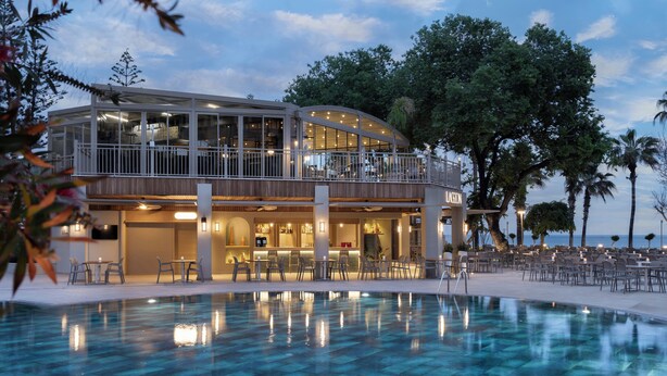 Een modern hotel met een zwembad, terras en een bar.