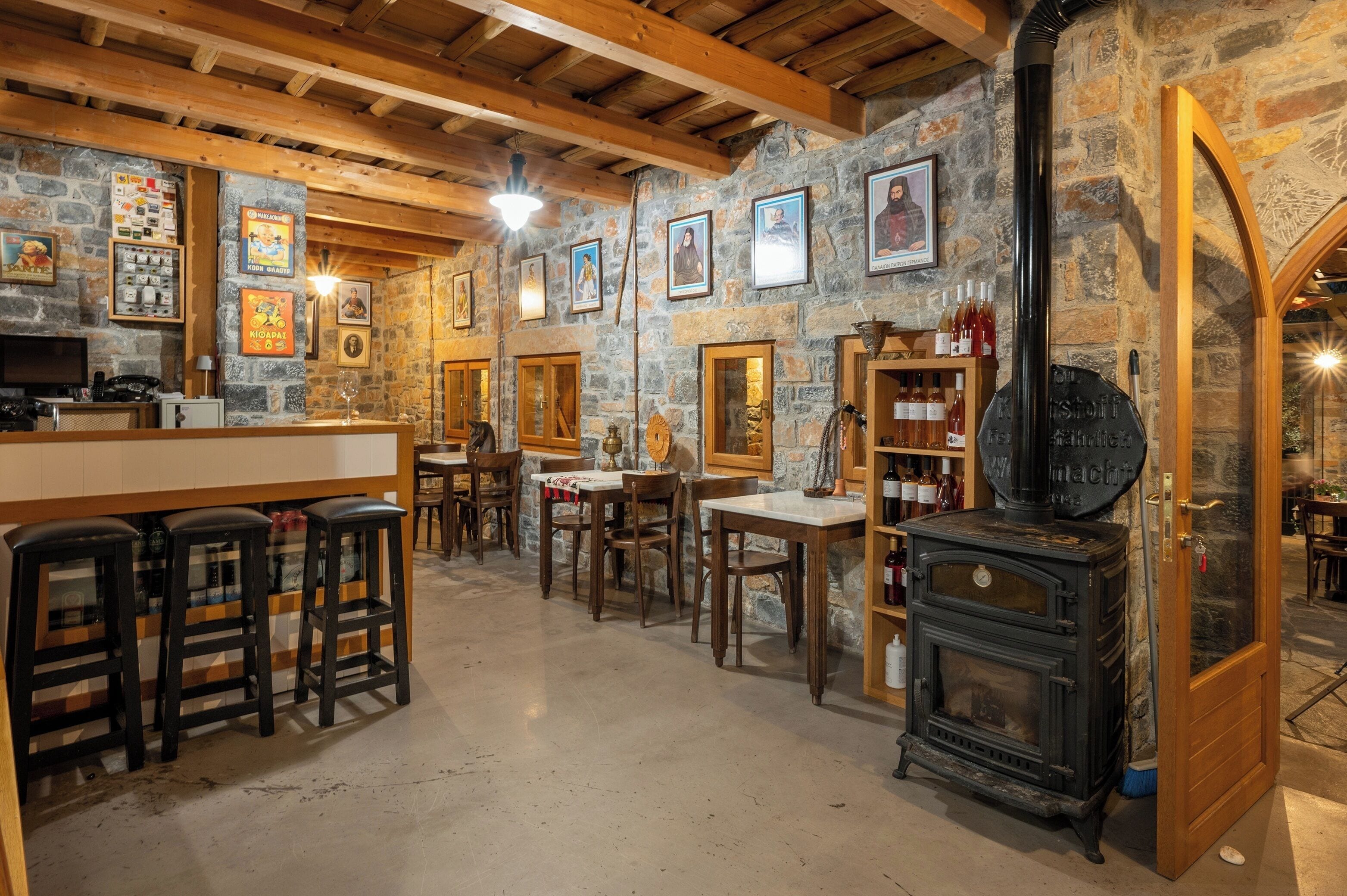 A rustic interior with stone walls, wooden beams, and a central wood-burning stove.