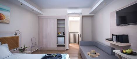 Una camera d'albergo moderna con un letto, un'area salotto, una TV e angolo cottura.